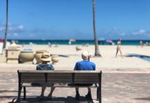 Hørelsen forsvinder, men det gør rejselysten ikke! Gammel mand og dame sidder på bænk i udlandet